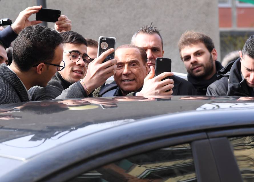 Forza Italia party leader Silvio Berlusconi poses for a selfie after casting his vote at a polling station in Milan