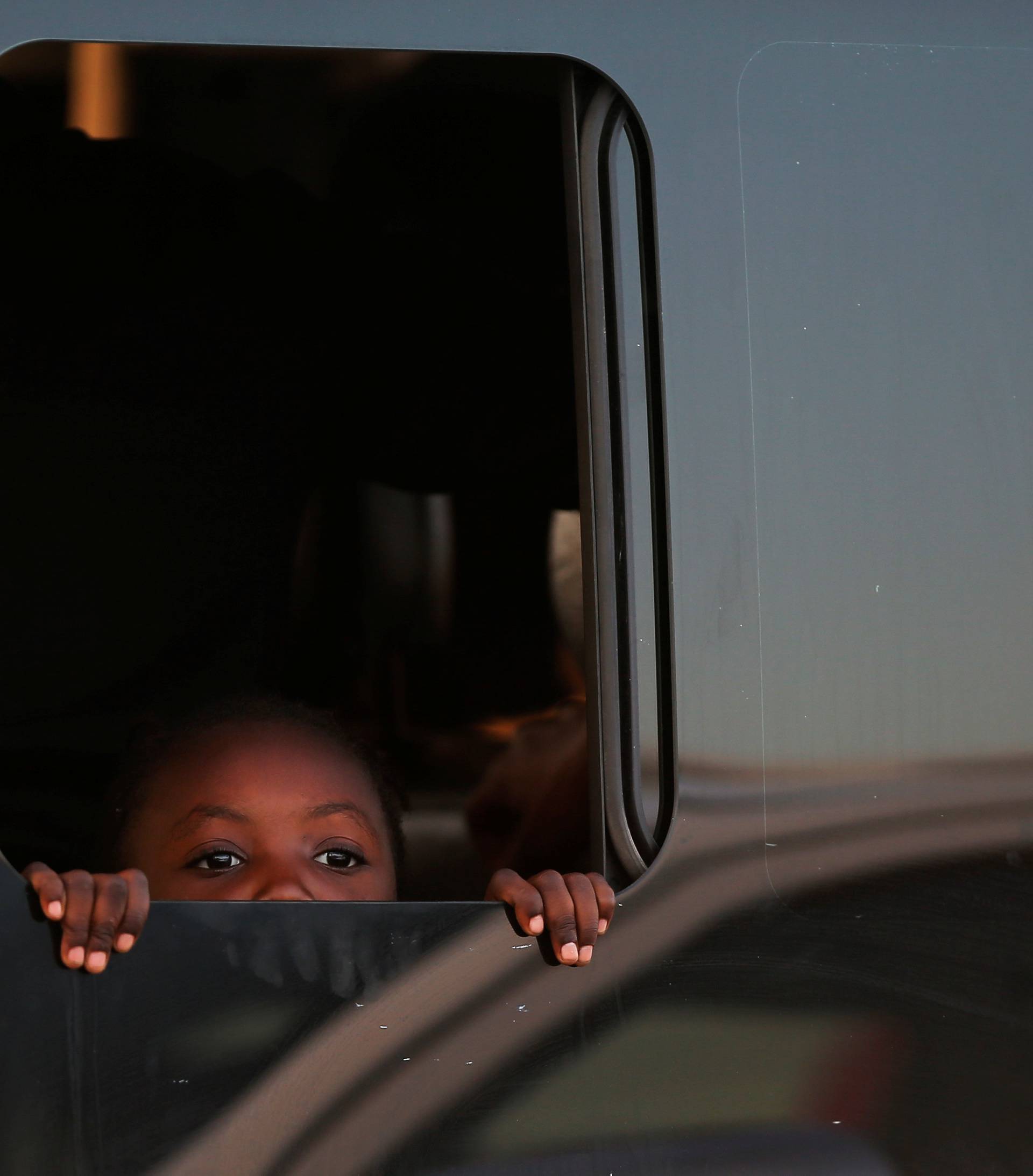A migrant child looks on through the window of a wagon after arriving on a rescue boat at the port of Malaga