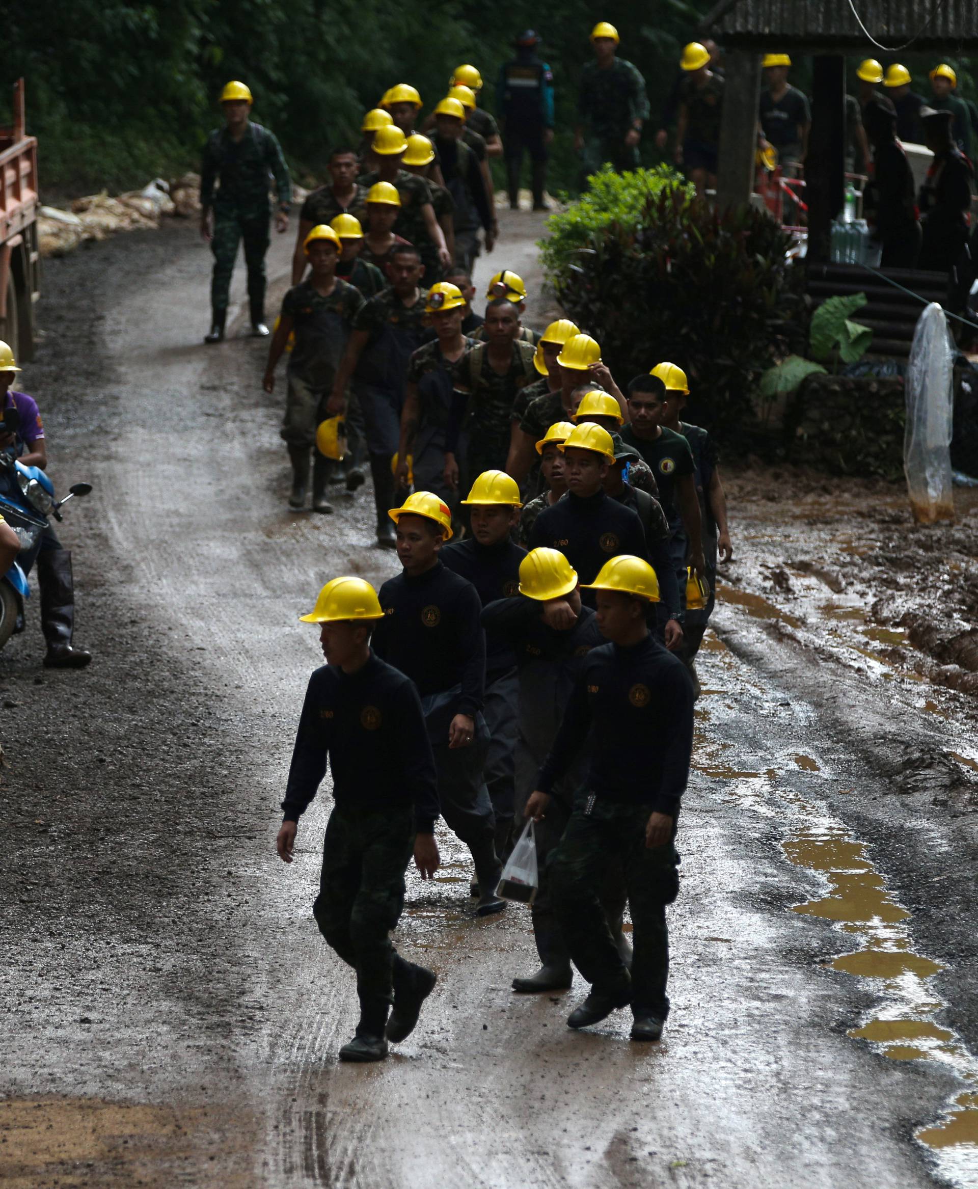 Military personnel walk in line as they prepare to enter the Tham Luang cave complex, where 12 boys and their soccer coach are trapped, in the northern province of Chiang Rai