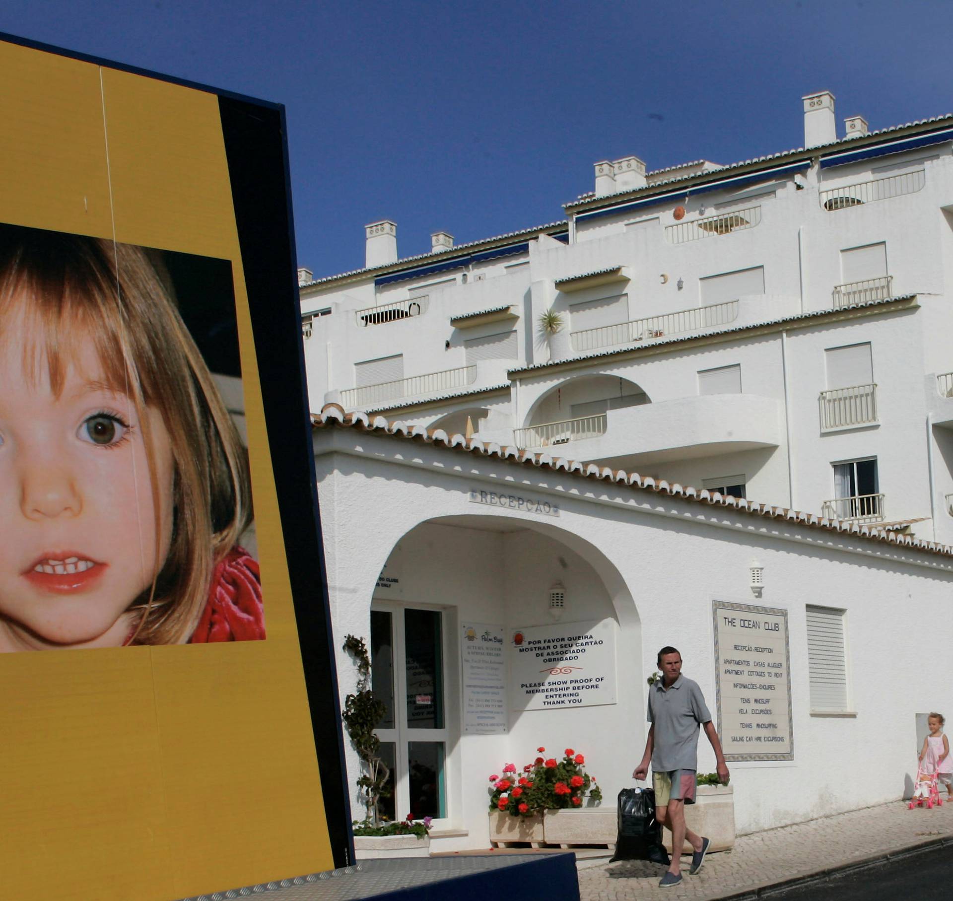 FILE PHOTO - People walk near a billboard at Praia da Luz tourist resort