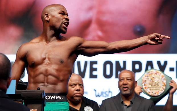 Undefeated boxer Floyd Mayweather Jr. of the U.S. points to UFC lightweight champion Conor McGregor of Ireland  during his official weigh-in at T-Mobile Arena in Las Vegas