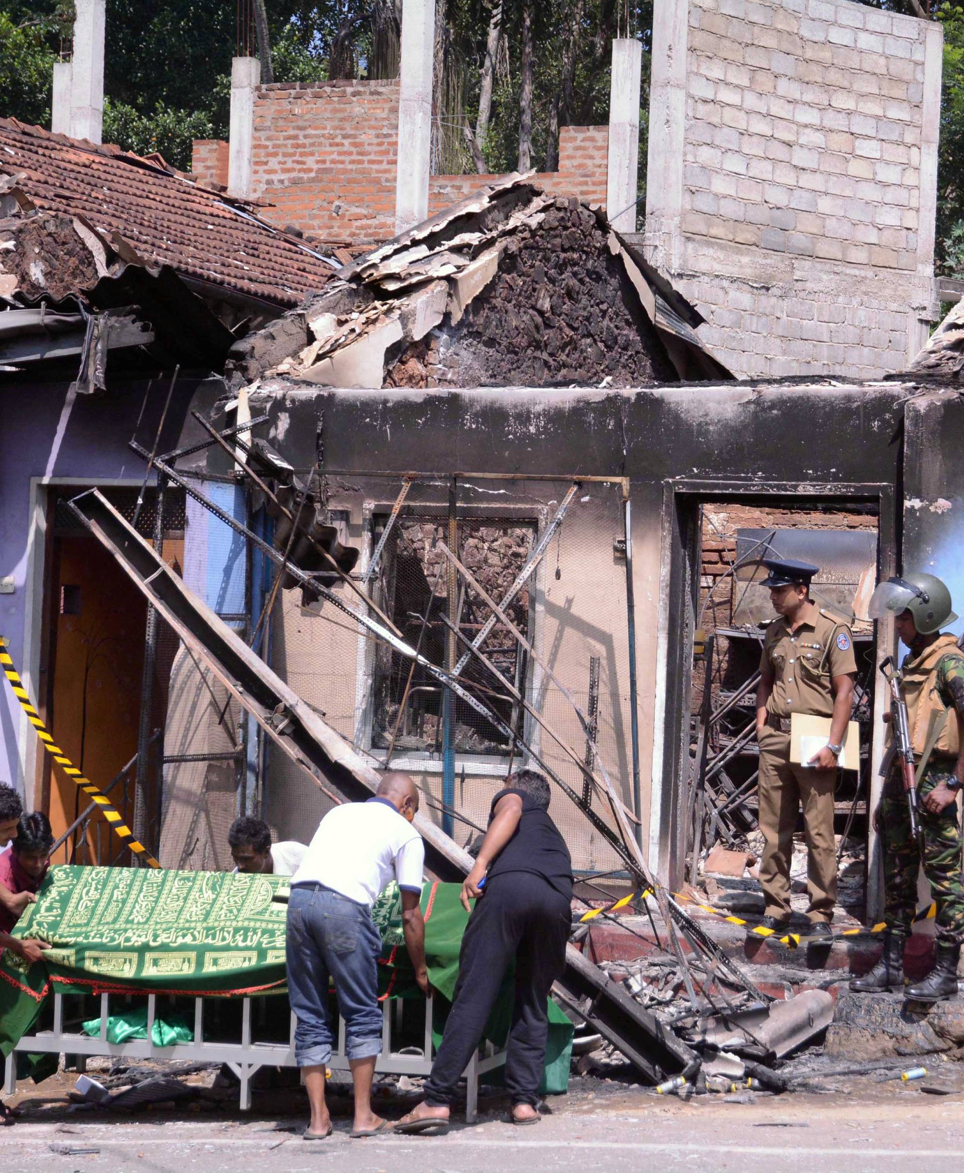 Sri Lanka's Special Task Force and Police officers stand guard near a burnt house after a clash between two communities in Digana, central district of Kandy