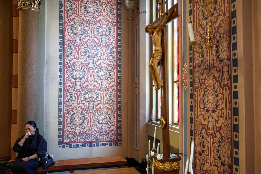 Catholic faithful watch a screen displaying the funeral service of Pope Francis at the Vatican, at the Assumption Cathedral, in Bangkok