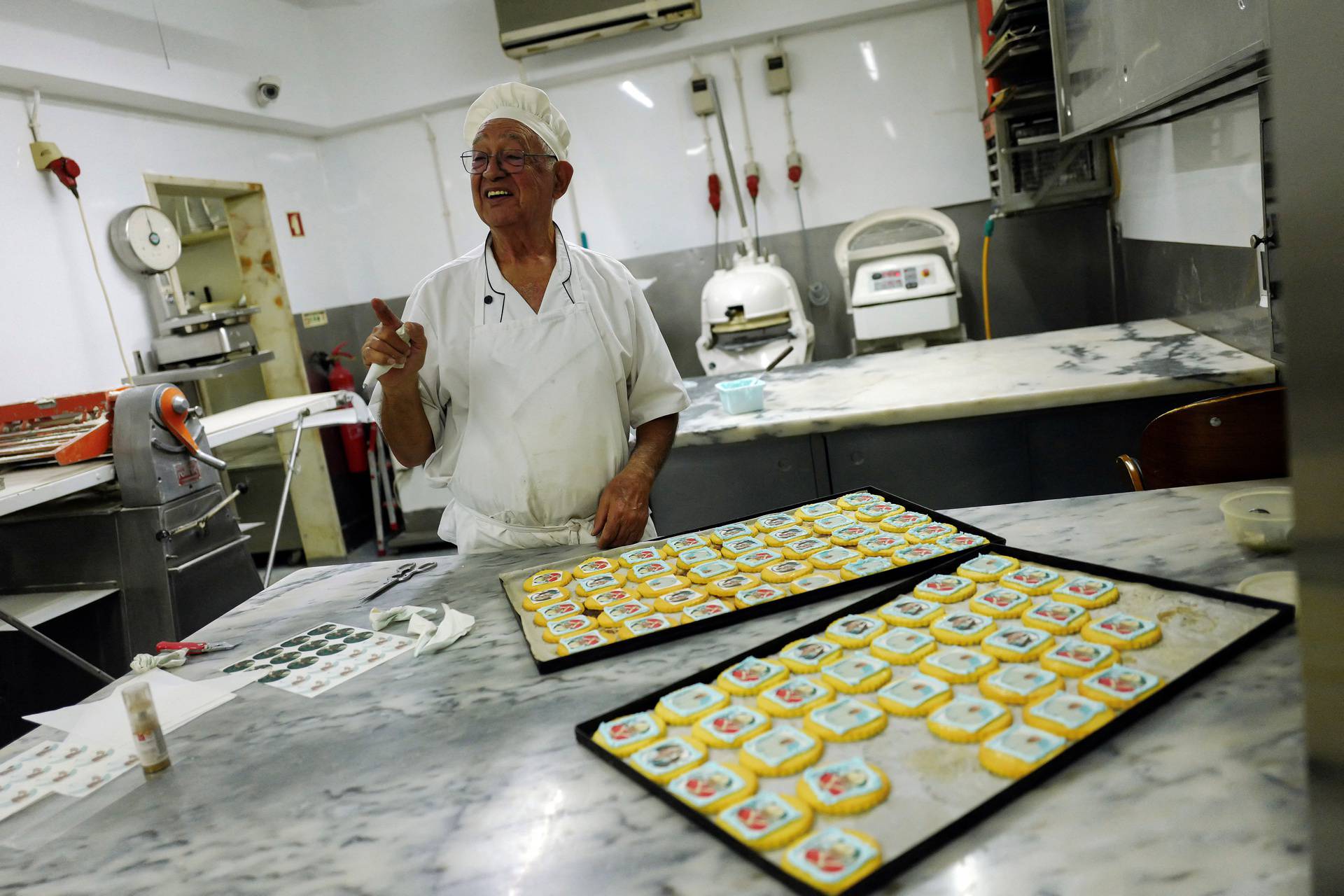 A pastry chef gestures as he prepares cookies with Pope Francis images ahead of his apostolic journey to Portugal, in Lisbon