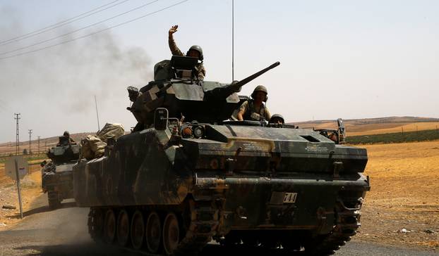 A Turkish soldier on an armoured personnel carrier waves as they drive from the border back to their base in Karkamis on the Turkish-Syrian border 