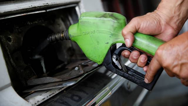 A gas station worker pumps gas into a car at a gas station of the state oil company PDVSA in Caracas
