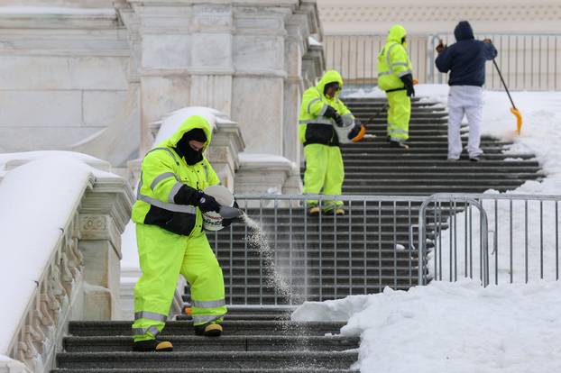 Workers spread salt and shovel the steps of the U.S. Capitol building after a winter storm in Washington
