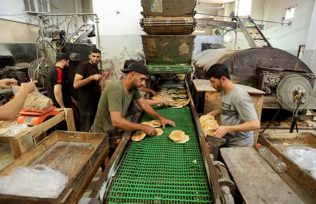 Palestinian workers make bread in a bakery that returned to operation after being closed due to a flour shortage, in Deir Al-Balah