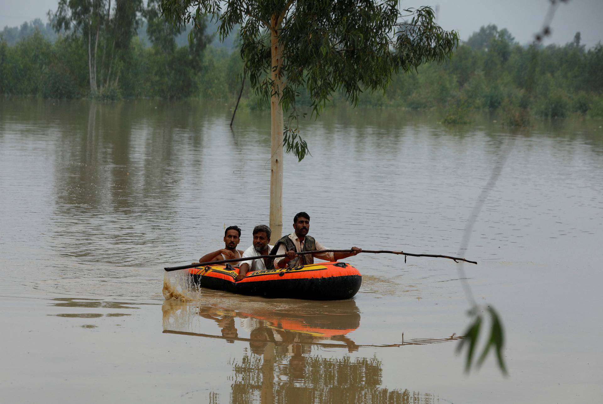 A volunteer rows an inflatable boat as he evacuates flood victims, following rains and floods during the monsoon season in Charsadda