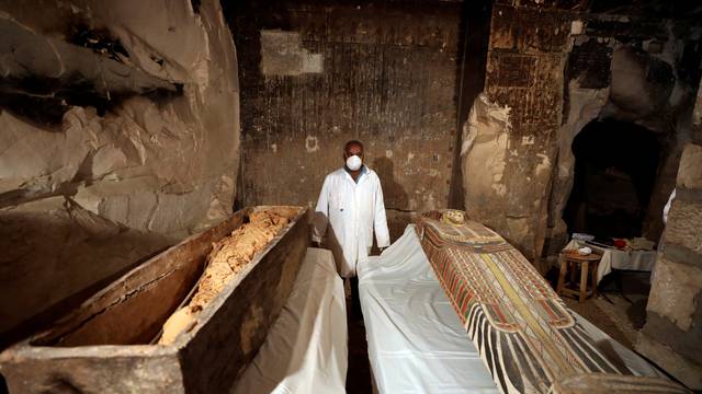 An archaeologist  stands near an intact sarcophagus inside the tomb TT33 in Luxor