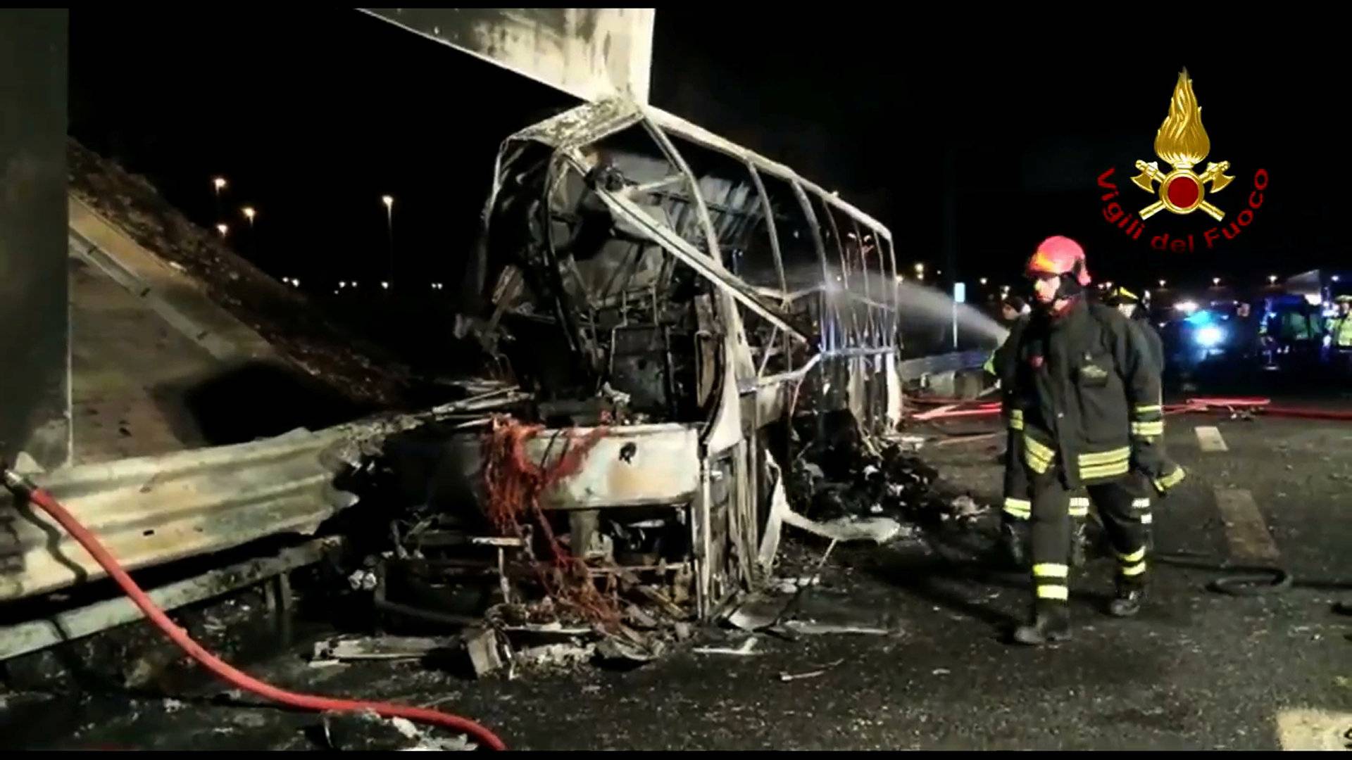 A still image taken from a video shows firefighters working next to a charred bus, which was carrying Hungarian students, on a side of a highway, near Verona