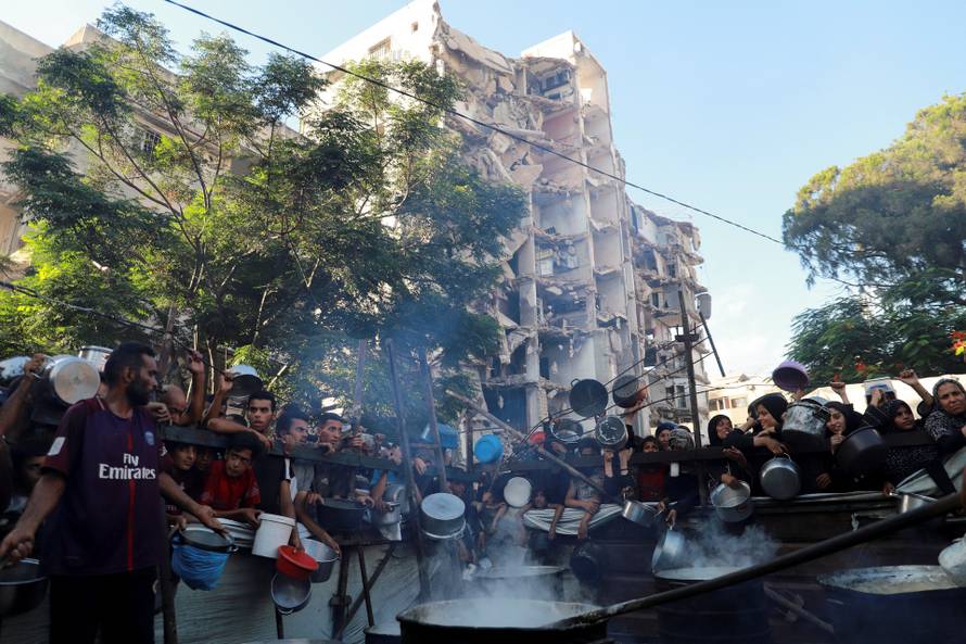 Palestinians wait to receive food from a charity kitchen amid hunger crisis, in Gaza City
