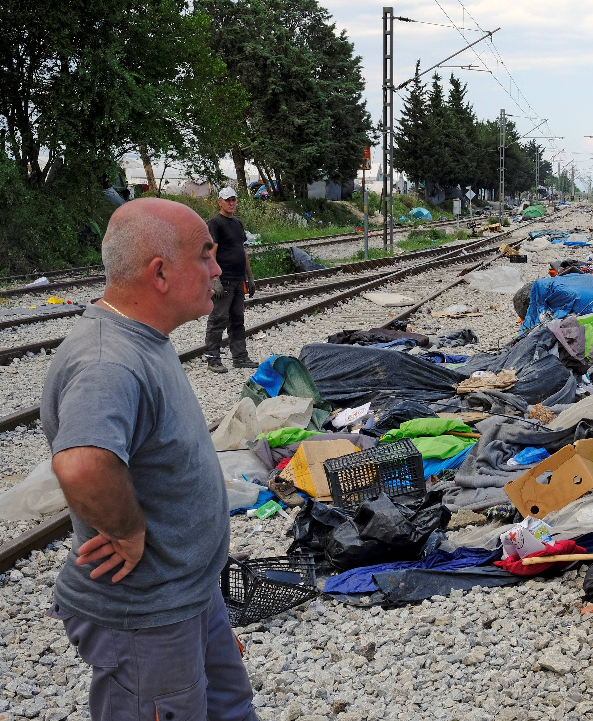 Workers stand on railway tracks during a police operation to evacuate a migrants' makeshift camp at the Greek-Macedonian border near the village of Idomeni