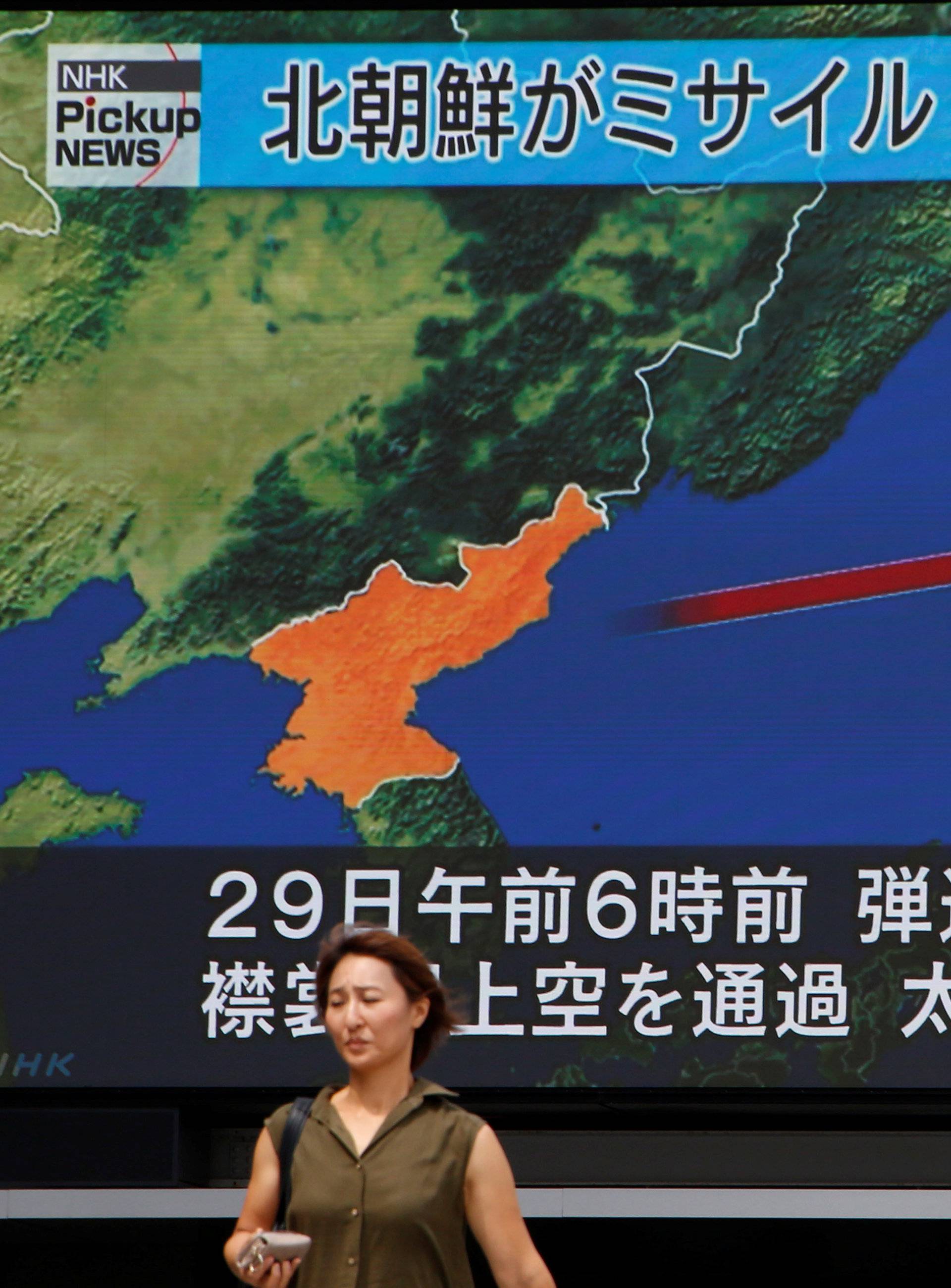 A woman walks past a large TV screen showing news about North Korea's missile launch in Tokyo