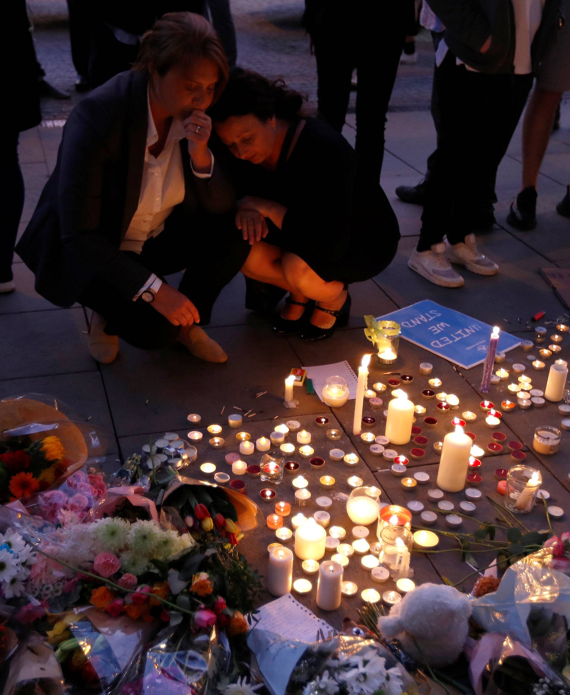 Women pay their respects to all those affected by the bomb attack, following a vigil in central Manchester