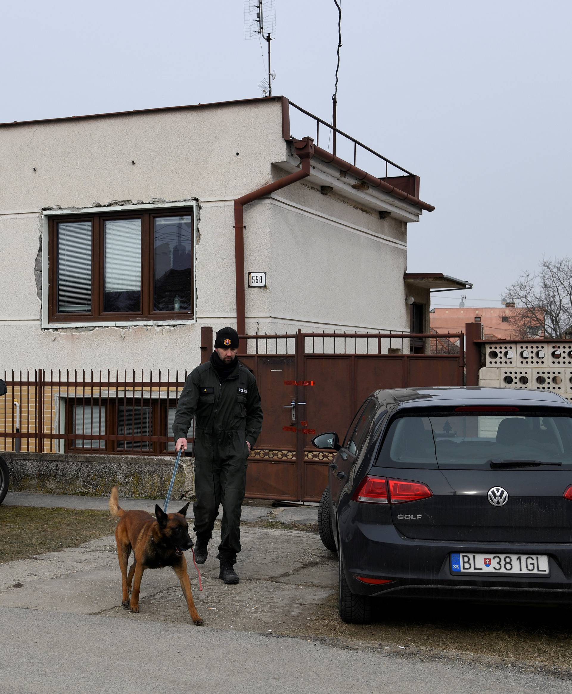 A police officer with a dog is seen near a house where Slovak investigative journalist Jan Kuciak and his girlfriend Martina Kusnirova lived and were murdered in the village of Velka Maca