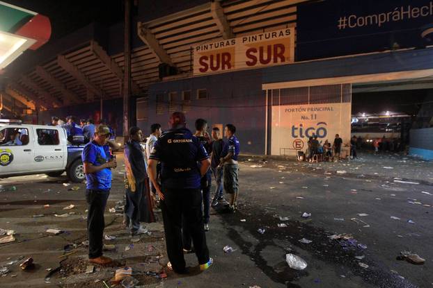 People stand outside at the National Stadium after an stampede when hundreds of fans tried to break past barricades in Tegucigalpa