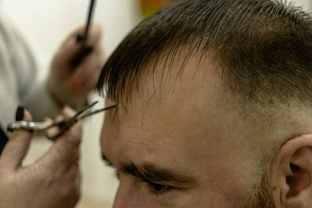 A man during a haircut. female hands of the master