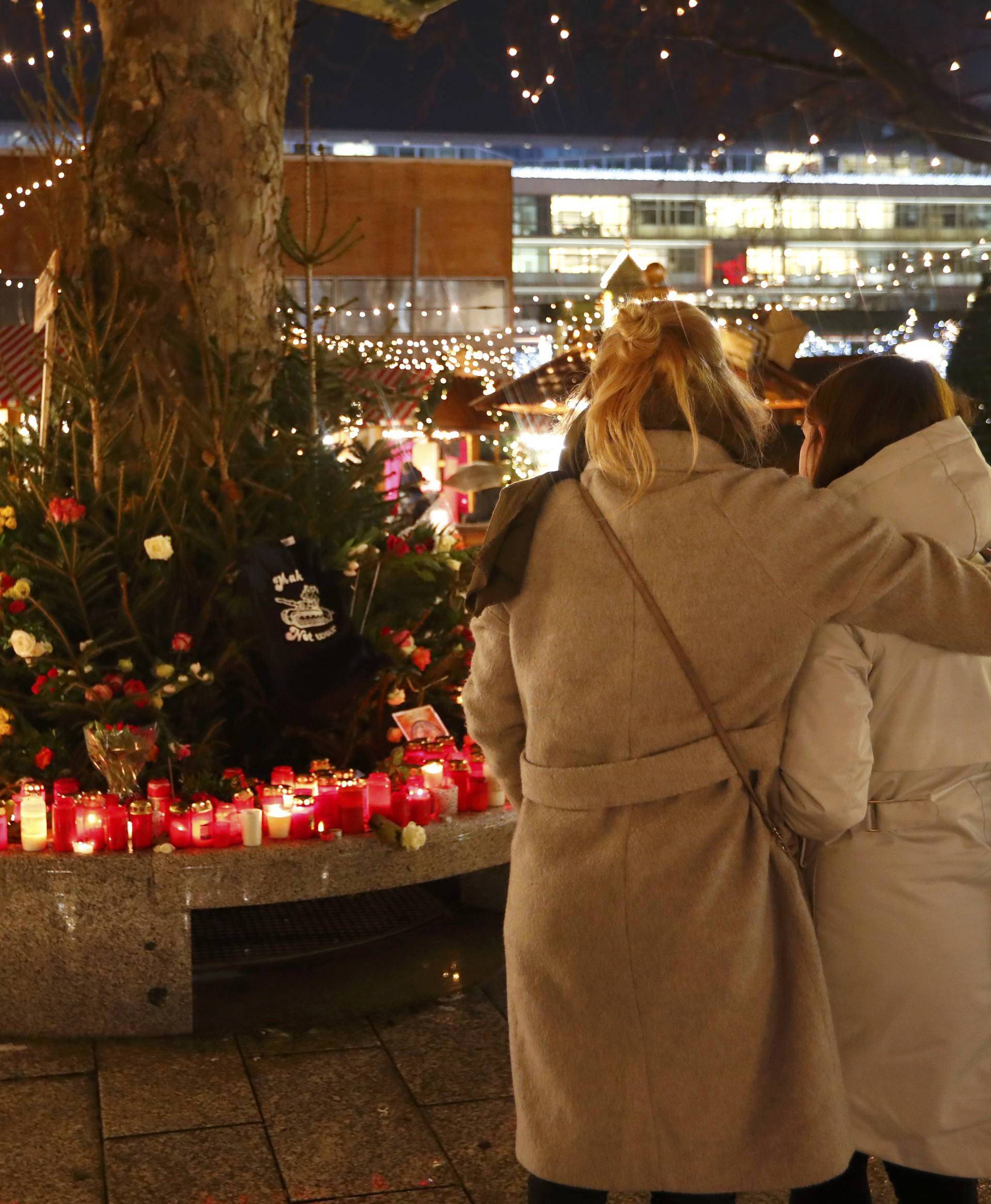 People mourn beside flowers and candles placed at the Christmas market at Breitscheid square in Berlin