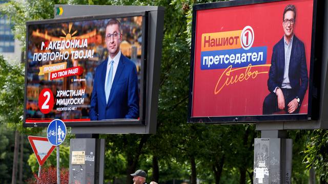 People walk past campaign billboards for the upcoming parliament and presidential elections in Skopje