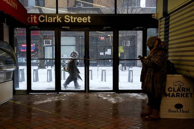 A woman takes shelter inside the entrance to the Clark Street subway station, in Brooklyn