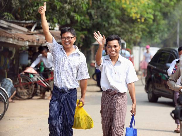 Reuters reporters Wa Lone and Kyaw Soe Oo gesture as they walk to Insein prison gate after being freed, after receiving a presidential pardon in Yangon