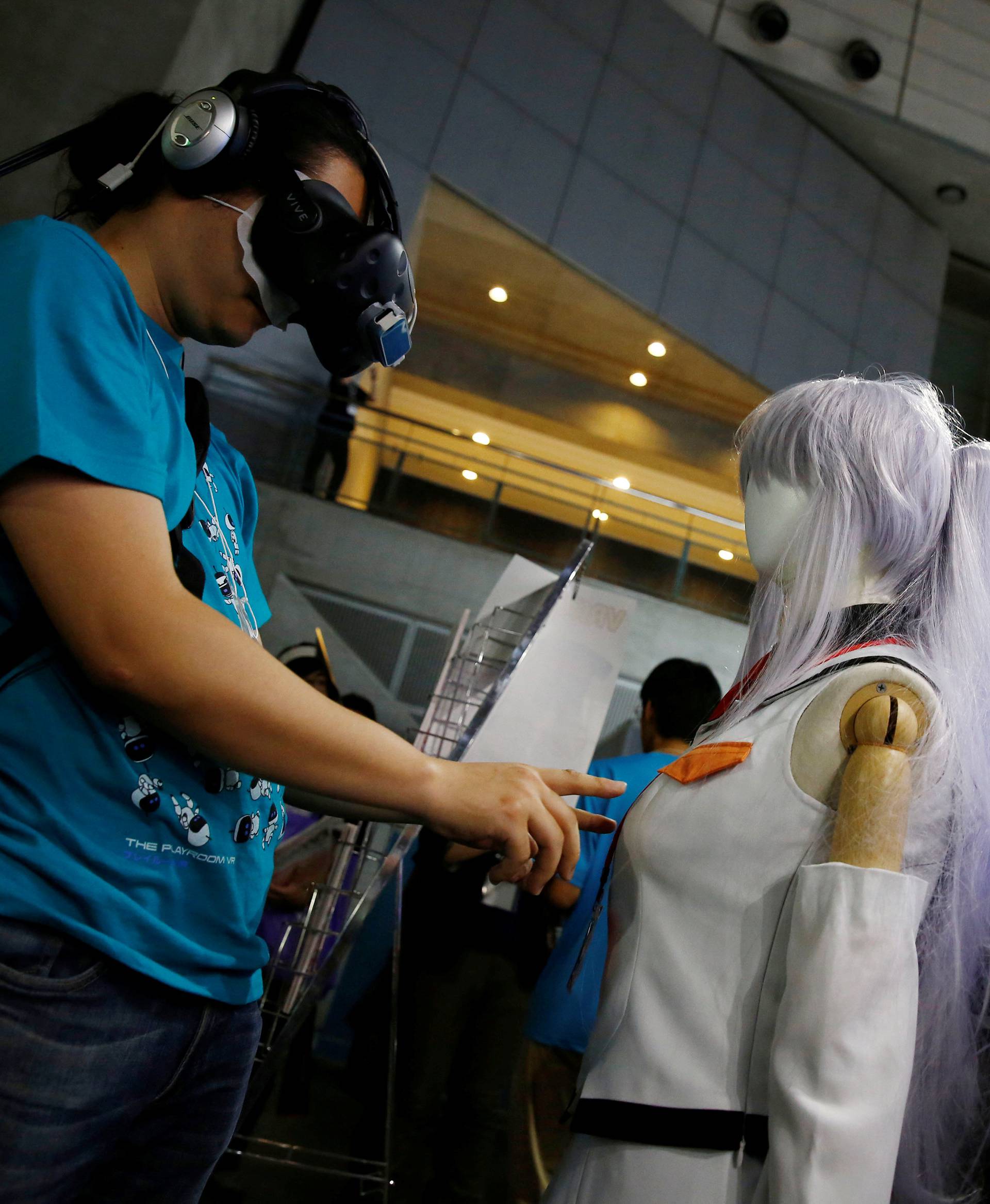 A man touches a mannequin as he tries out a M2 Co.Ltd's "E-mote" system at Tokyo Game Show 2016 in Chiba