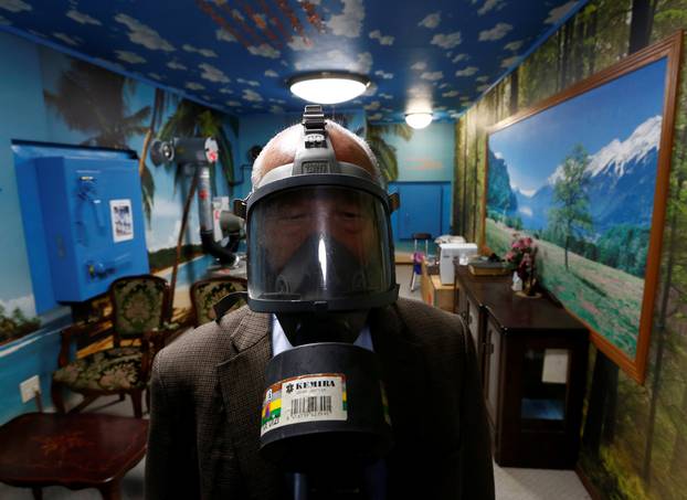 Seiichiro Nishimoto, CEO of Shelter Co., poses wearing a gas mask at a model room for the company
