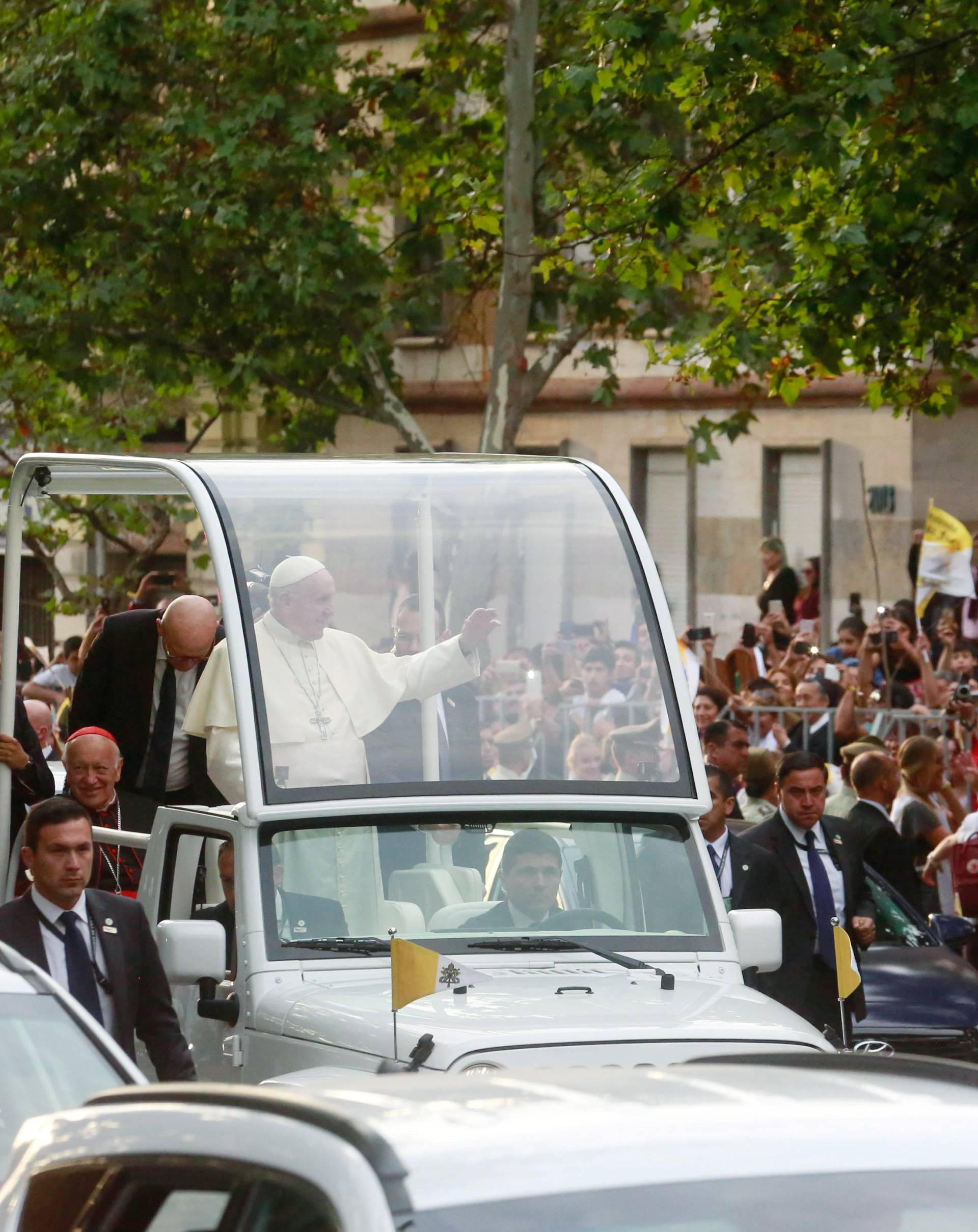 Pope Francis waves to people while driving through Santiago