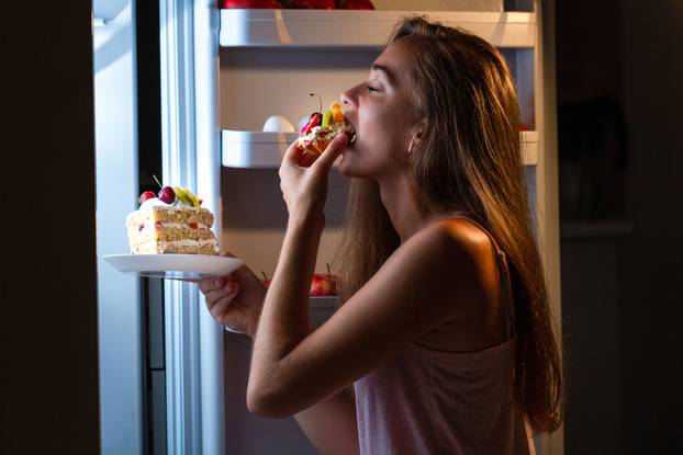 Hungry,Woman,In,Pajamas,Eating,Sweet,Cakes,At,Night,Near