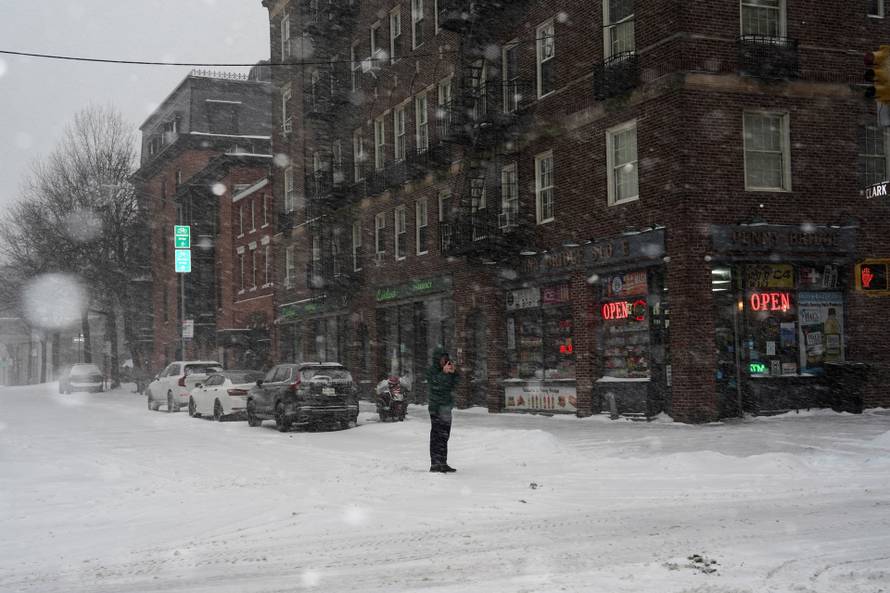 A pedestrian uses his mobile phone to photograph snowfall, in Brooklyn