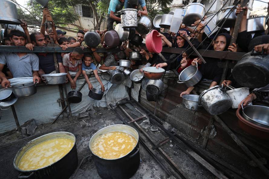Palestinians wait to receive food from a charity kitchen, amid a hunger crisis, in Gaza City