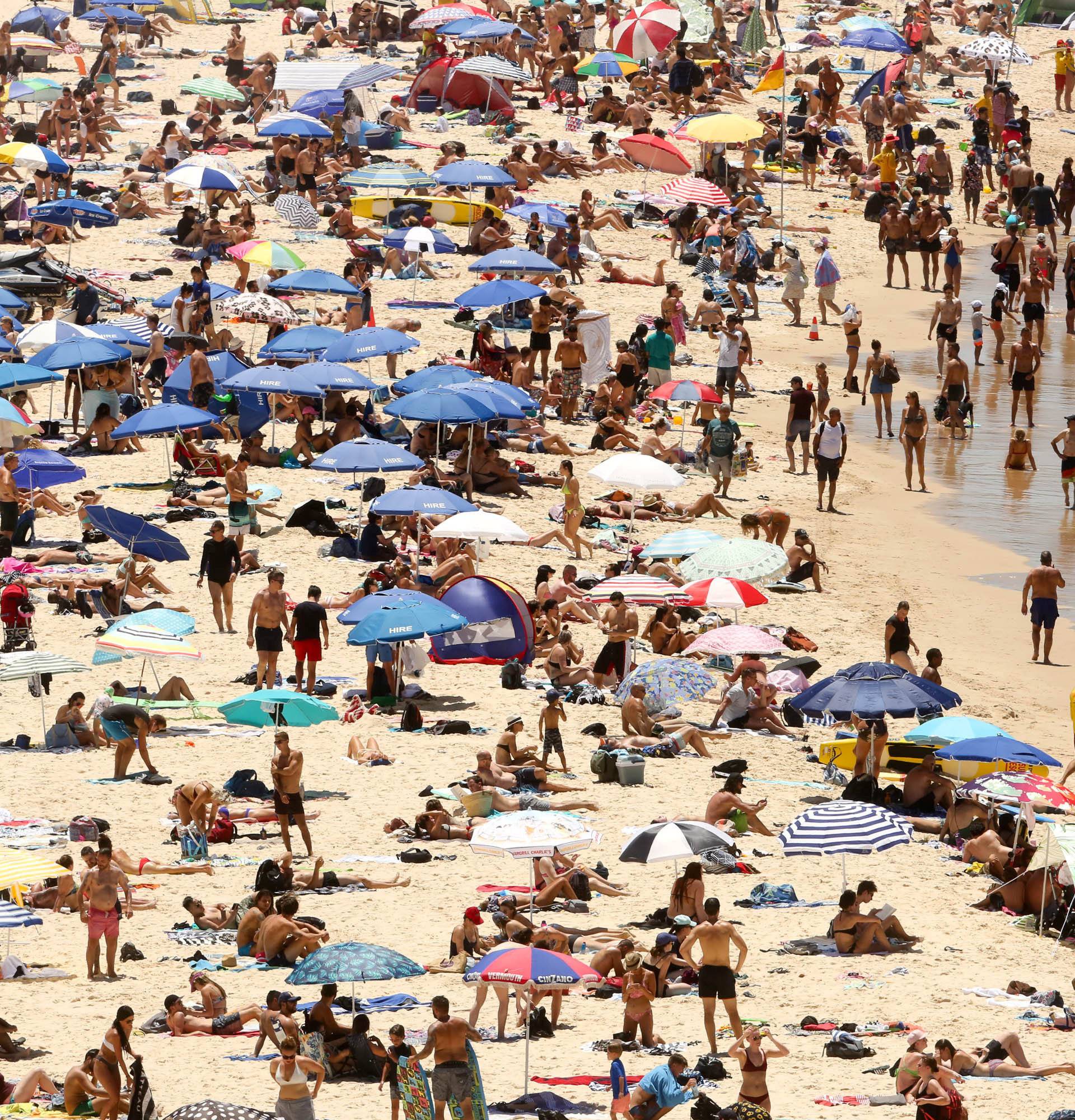 Beachgoers sit and walk in the water at Sydney's Bondi Beach on a hot summer day in Australia