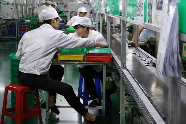 Employees work at a production line of lithium ion batteries inside a factory in Dongguan