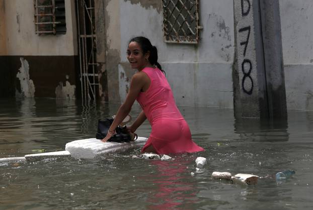 A woman keeps her shoes dry on a piece of foam board while wading through a flooded street, after the passing of Hurricane Irma, in Havana