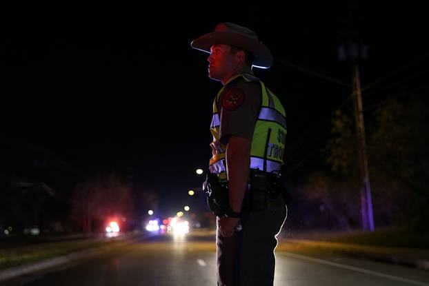 A Texas state trooper keeps watch at a checkpoint as nearby law enforcement personnel investigate an incident in Austin