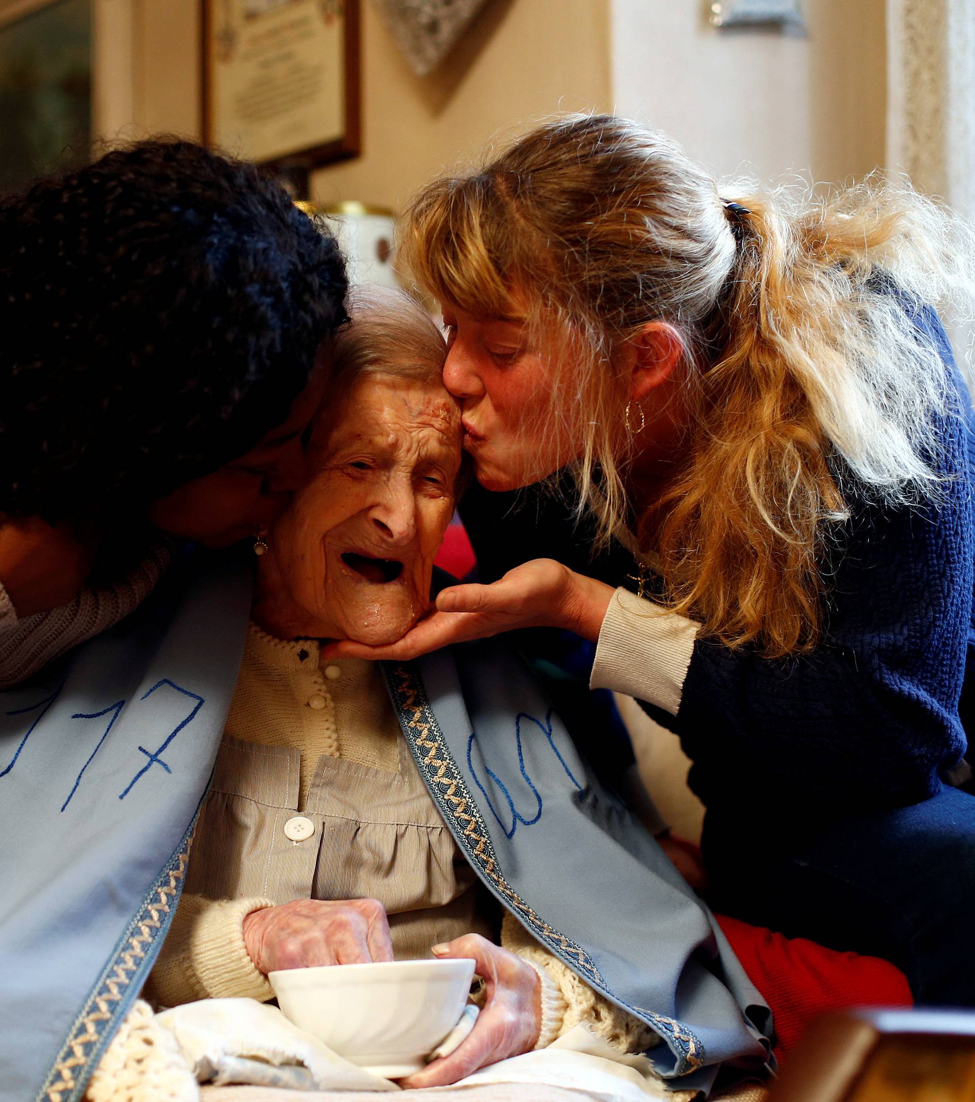 Emma Morano is kissed by her caretakers Ceglinska and Vergara during the 117th birthday in her house in Verbania