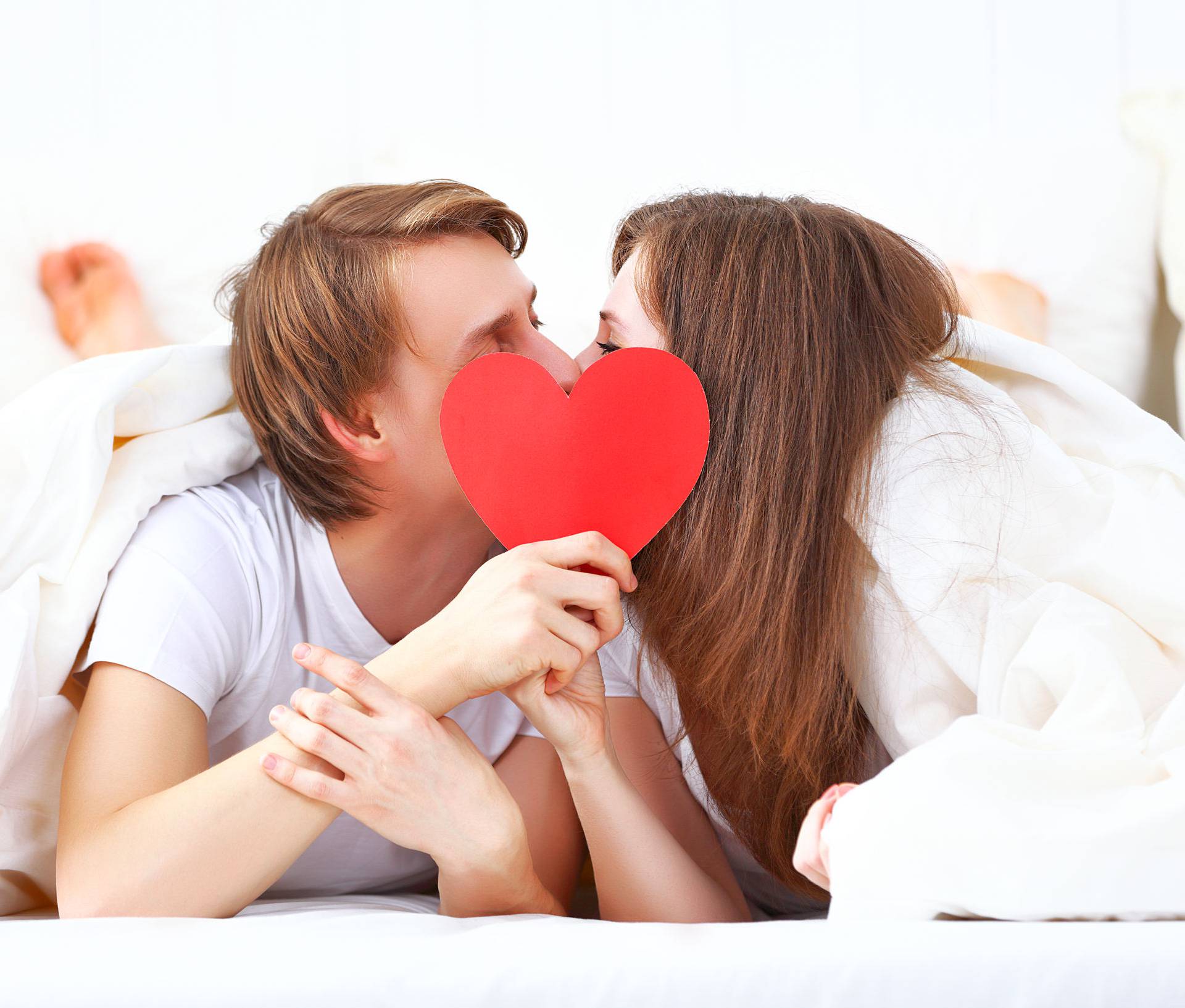 lover couple kissing with a red heart in bed