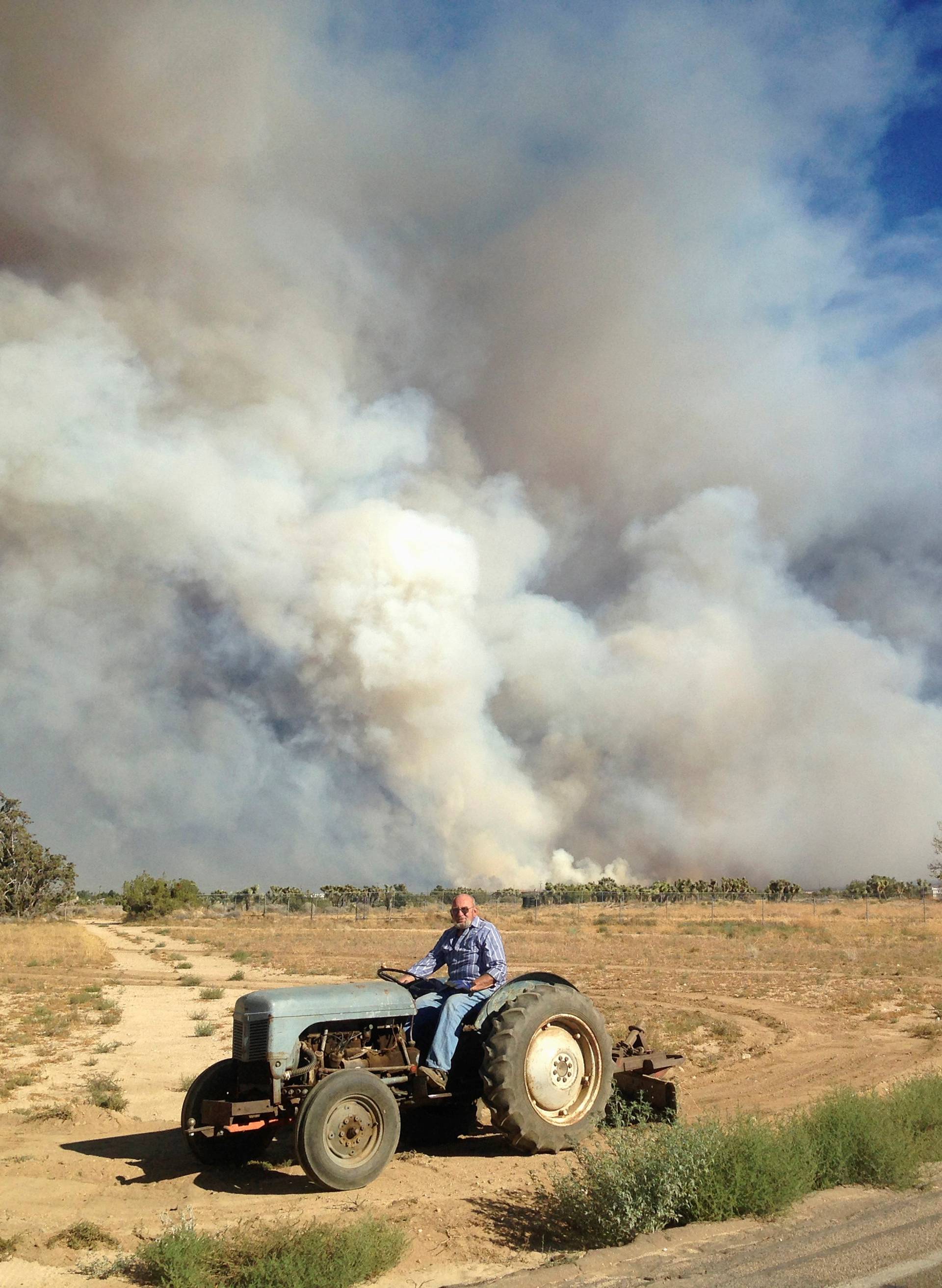 Property owner Jim Watson uses a tractor to make a fire break for his neighbors at the so-called Bluecut Fire in San Bernardino County, California