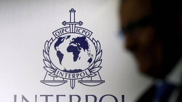 FILE PHOTO: A man passes an Interpol logo during the handing over ceremony of the new premises for Interpol's Global Complex for Innovation in Singapore