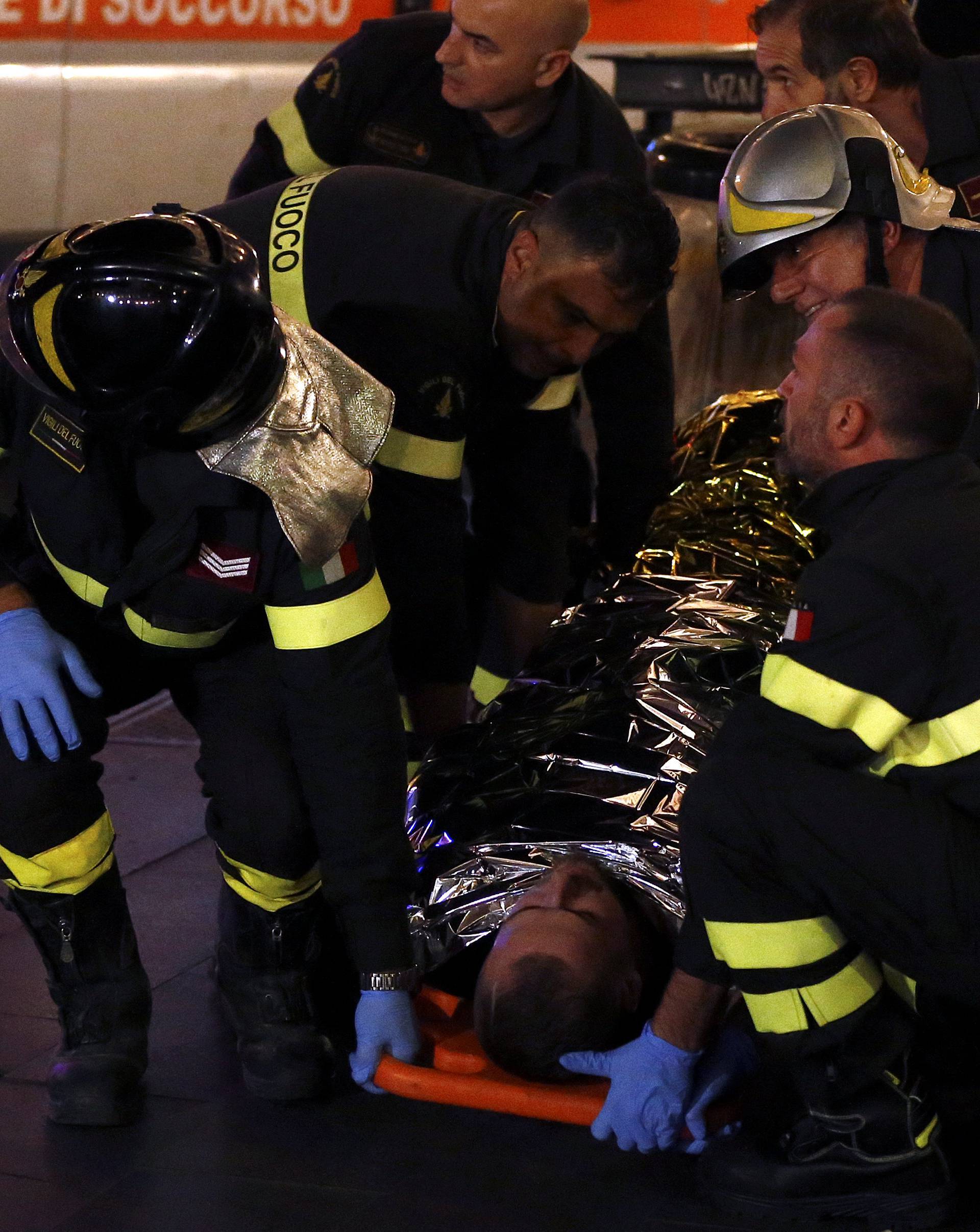 Fire fighters carry an injured person outside the underground where some of CSKA Moscow supporters were injured in Rome