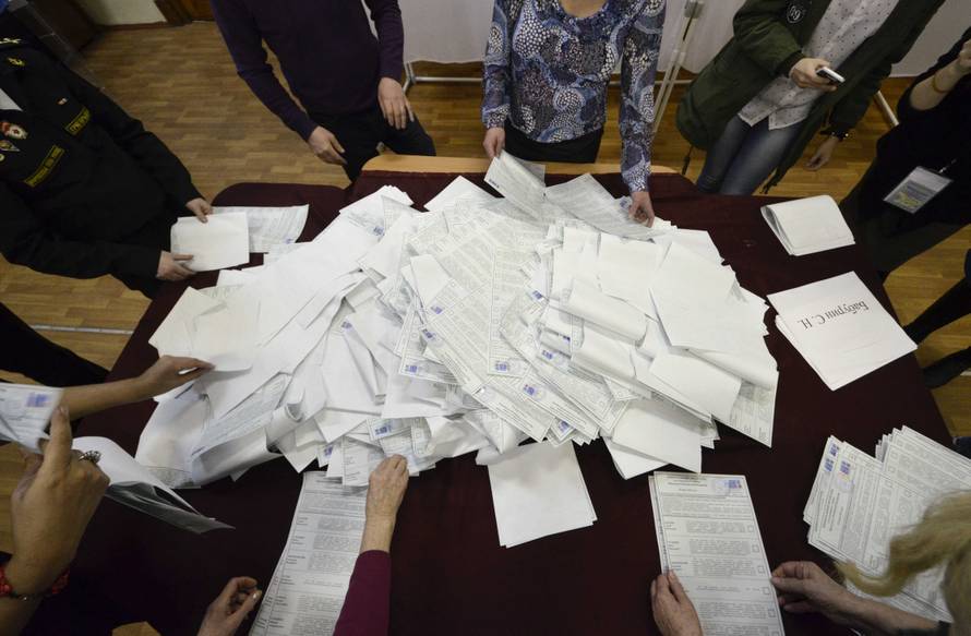 Members of a local election commission sort ballots before starting to count votes during the presidential election in Vladivostok