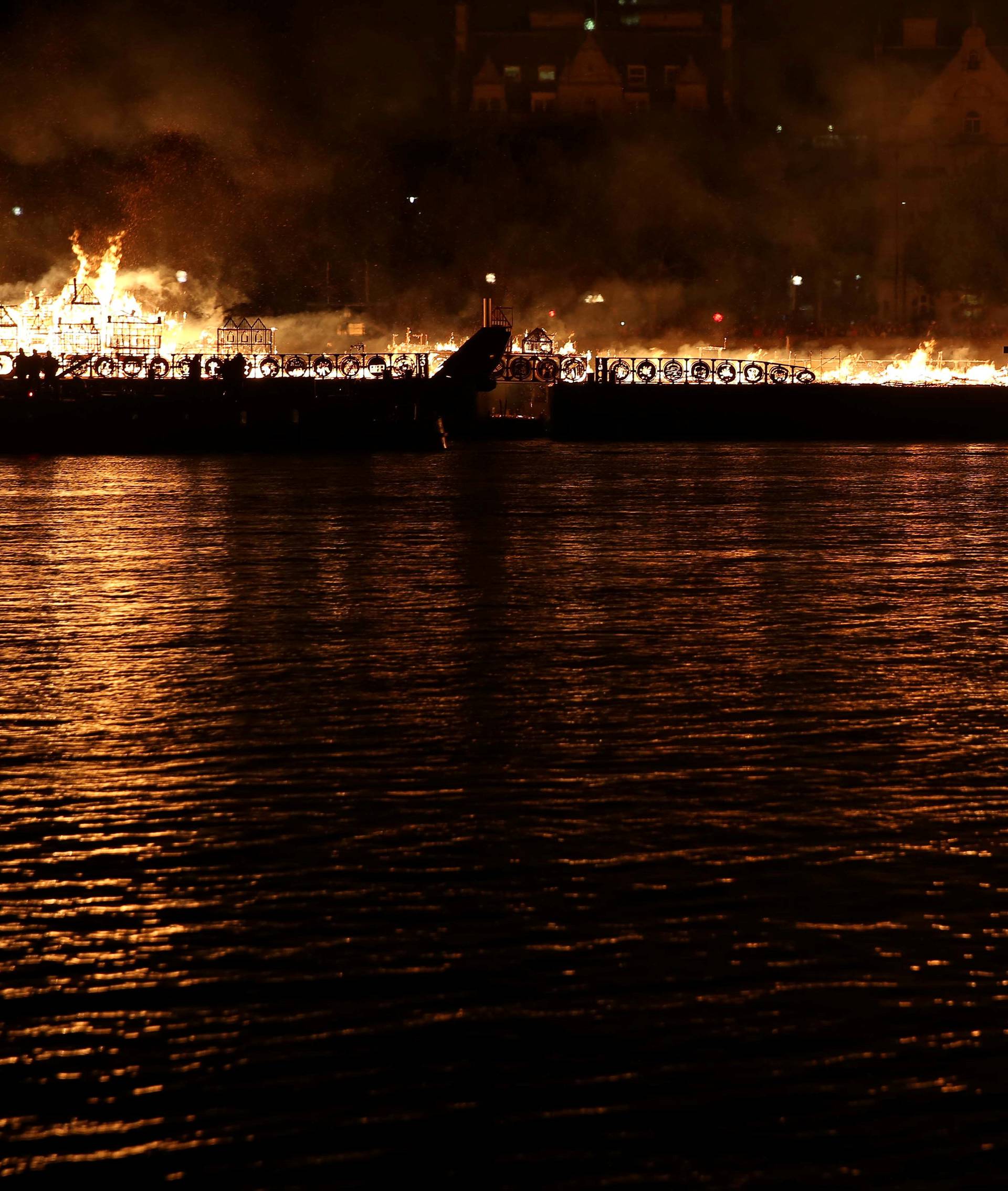 A boy watches as a 120-meter long model of the 17th century London skyline is set alight on the River Thames to commemorate the 1666 Great Fire of London in London