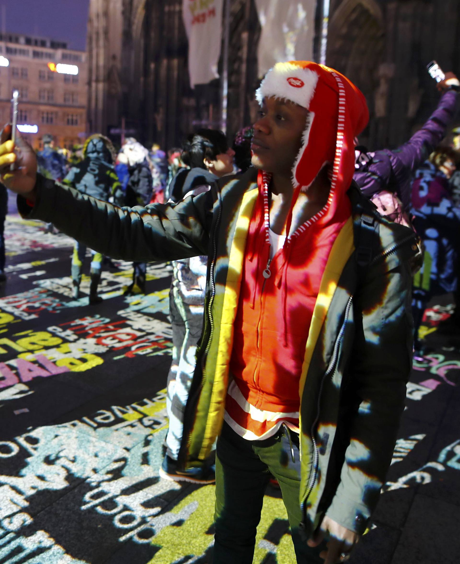 A refugee Joseph from Kenia takes a selfie during the laser installation "Time Drifts Cologne" before New Year celebrations for 2017 in Cologne