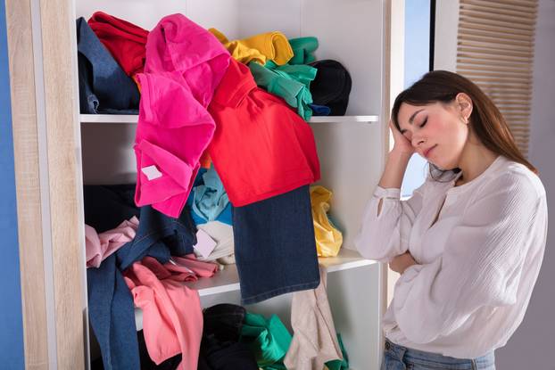 Woman Sleeping Near Messy Clothes On Shelf