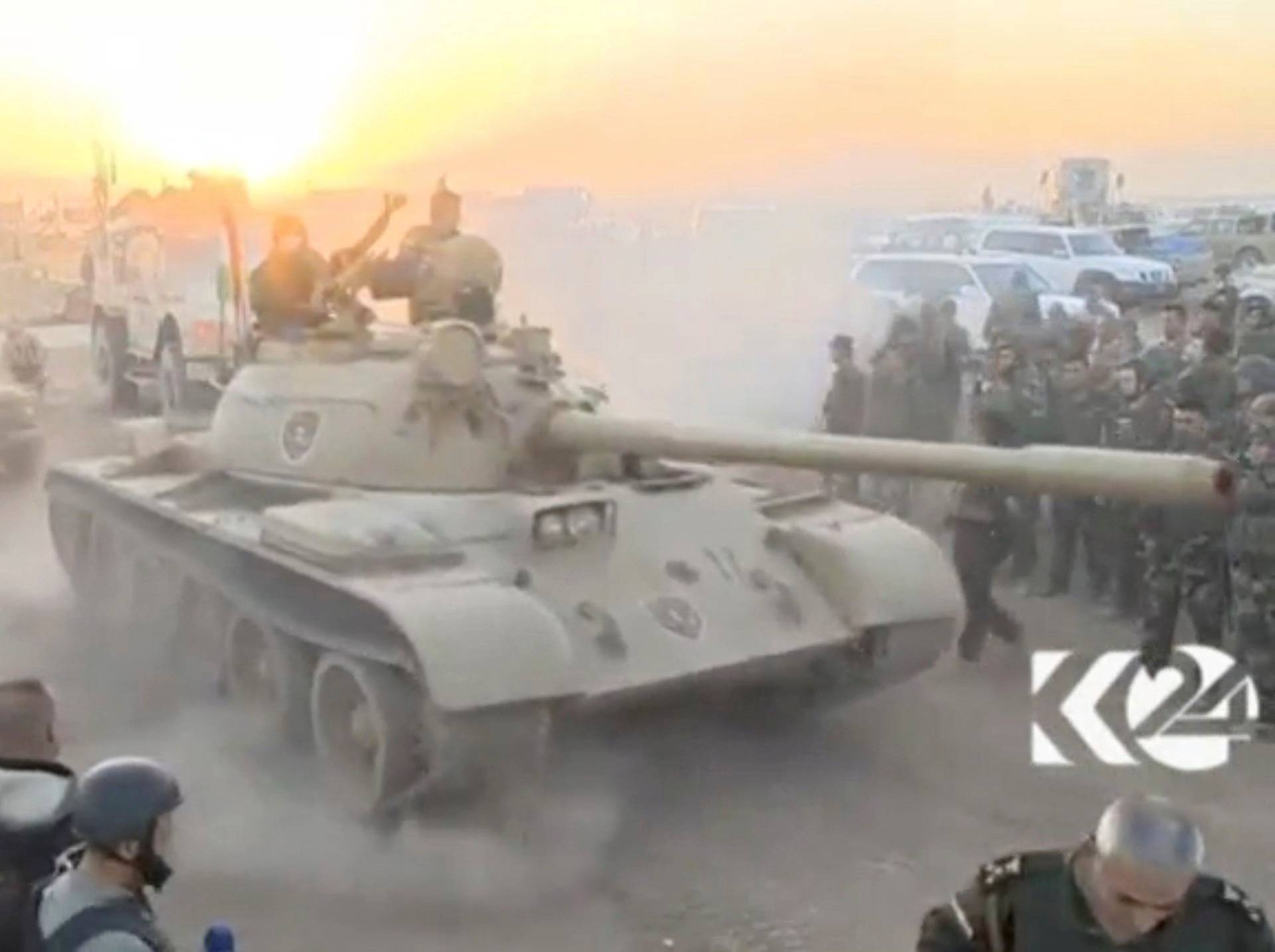 Tanks move past soldiers in military fatigues as the sun begins to set east of Mosul, where the Iraqi government launched a U.S.-backed offensive to drive Islamic State from the northern city, in this still image taken from video