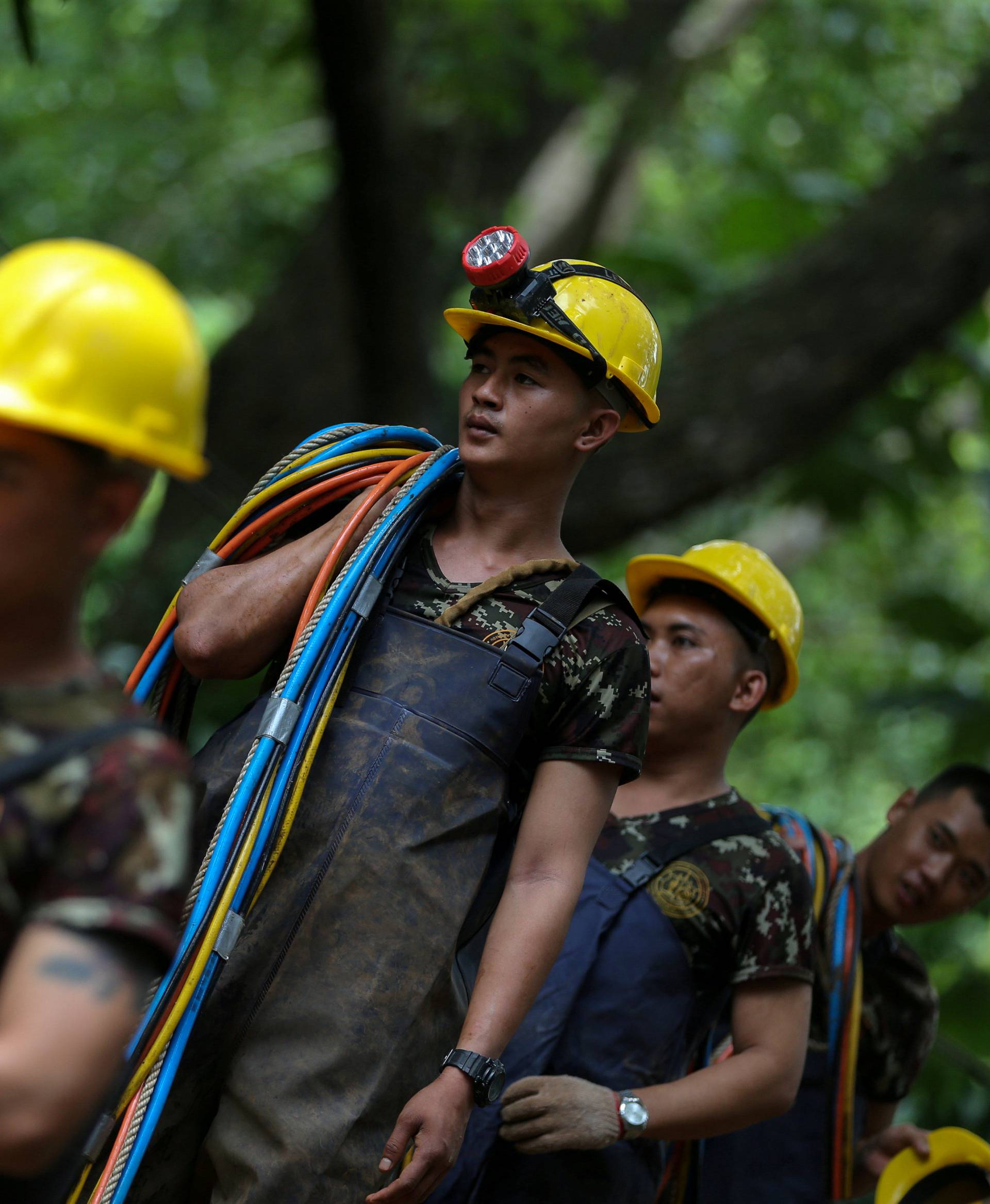 Military personnel carry surface supply diving cables out from Tham Luang cave complex, as members of an under-16 soccer team and their coach have been found alive according to local media in the northern province of Chiang Rai
