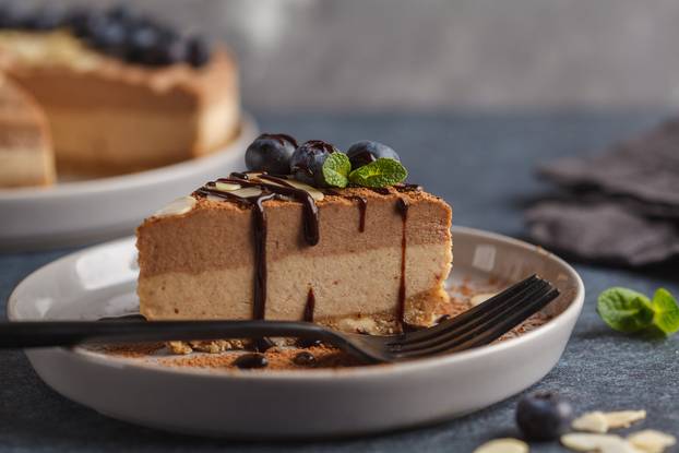 Piece of raw vegan chocolate-caramel cheesecake with blueberries