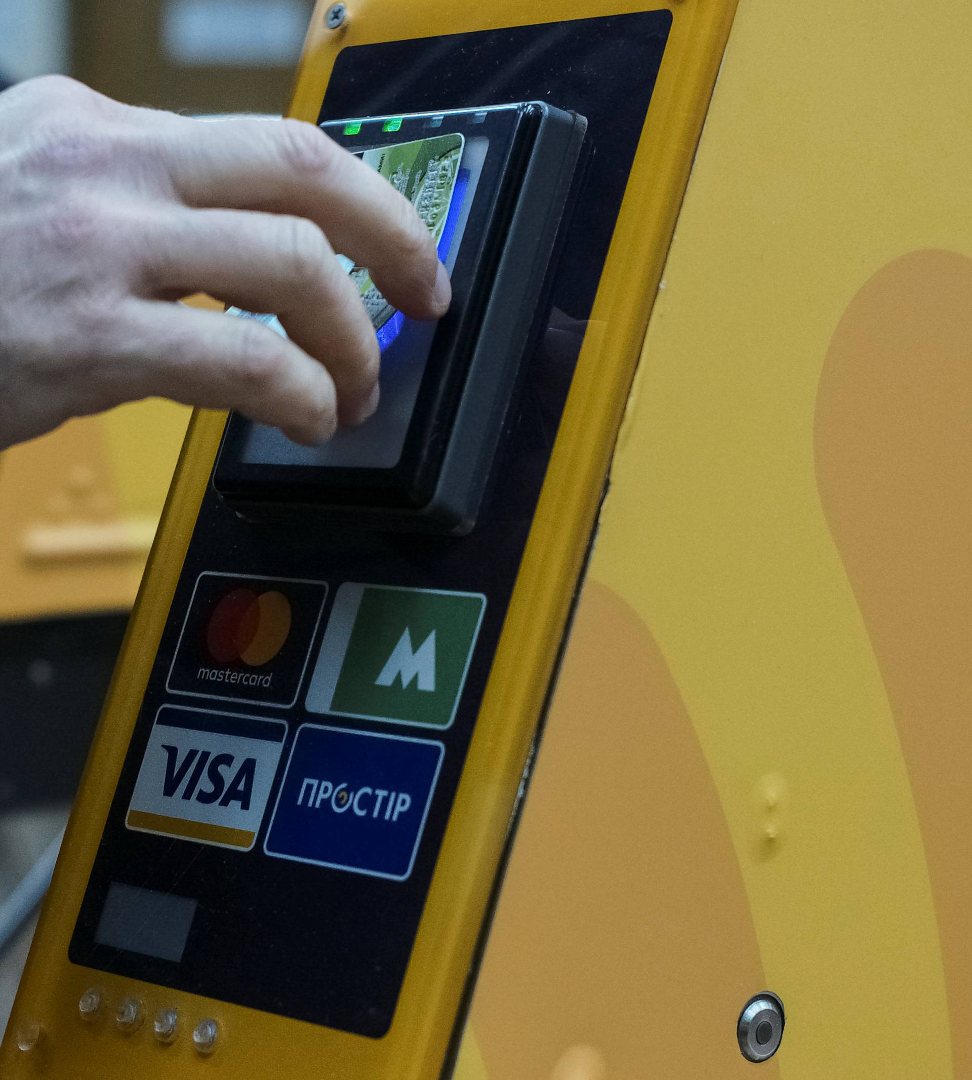 A passenger swipes a bank card against a terminal to ride the subway system in Kiev