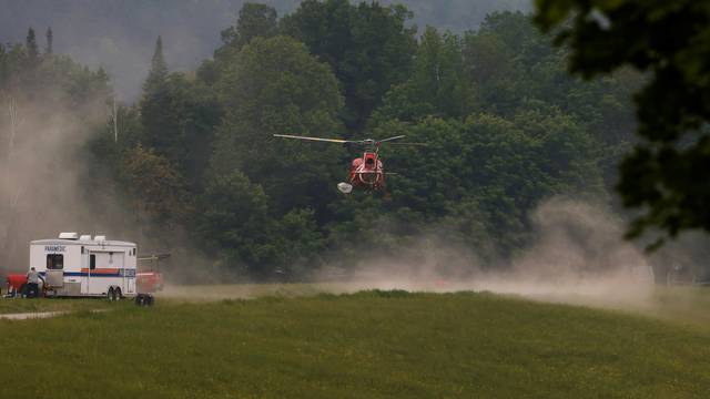 A helicopter lands in a staging area near a forest fire that has been burning since Sunday on the shore of Centennial Lake in the Township of Greater Madawaska